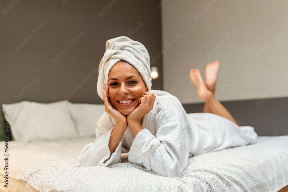 Young beautiful woman in towel and bathrobe laying on the bed and looking at the camera. Young beautiful woman in towel and bathrobe laying on the bed and looking at the camera.