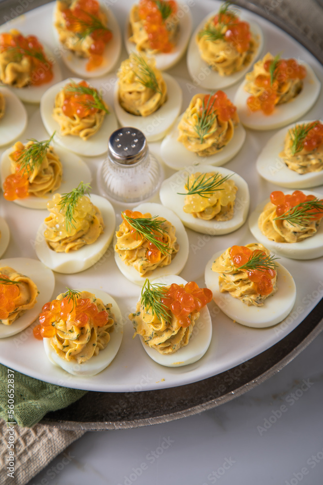 Gefüllte teuflische russische Eier mit Dill und orange Keta Lachs und gelb Saibling Kaviar auf Eierteller, Serviette grün, Silber Teller und Marmor Hintergrund hell Gefüllte teuflische russische Eier mit Dill und orange Keta Lachs und gelb Saibling Kaviar auf Eierteller, Serviette grün, Silber Teller und Marmor Hintergrund hell