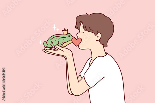 Guy kisses frog princess with crown on head, wishing that animal turned into beautiful girl. Teenage boy in white T-shirt holds green toad from fairy tales in hands. Flat vector illustration 