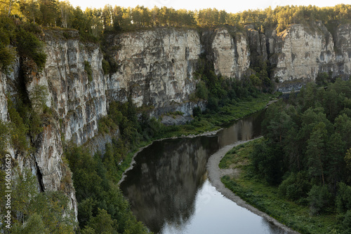 Breathtaking canyon with high rocky cliffs with thin curved river down below with reflections and lush green forest in golden sunbeams of morninig summer sun. Amazing mountain landscape for travel. photo