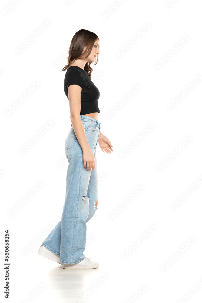 Young female model wearing ripped jeans and black shirt walking on a white background. Side, profilet view Young female model wearing ripped jeans and black shirt walking on a white background. Side, profilet view
