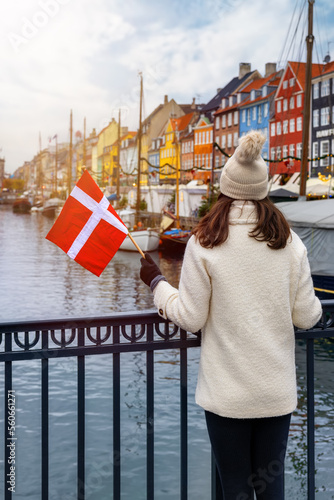Photography A tourist woman holding a Danish flag enjoys the view of the beautiful Nyhavn ar
