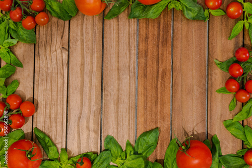 background of wooden slats surrounded by the edges with basil leaves and tomato at the bottom