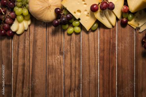 cheese board accompanied by red and white grapes on wood photo