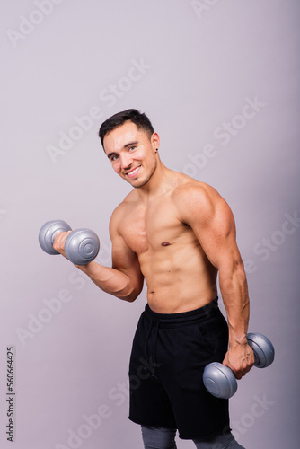 Shirtless bodybuilder showing his great body and holding dumbell.