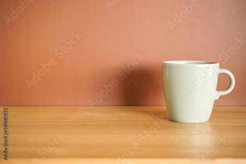Green Ceramic coffee mug on wood table with brown background