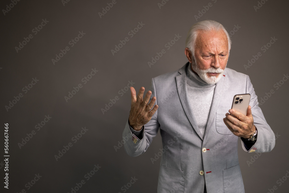 Senior businessman looking angry at his phone