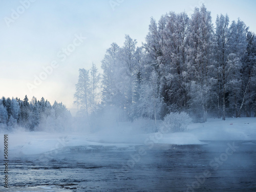 Strong frost in January on the Shuya River in the Republic of Karelia, northwestern Russia. Steam over water. The waterfall in the river is partially frozen.