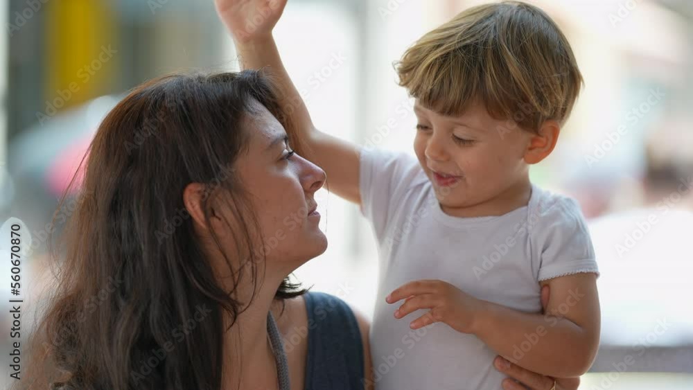 Cute lifestyle moment of mother and child hanging out together in sunny day outside. Little boy tapping mother head candid and authentic Cute lifestyle moment of mother and child hanging out together in sunny day outside. Little boy tapping mother head candid and authentic