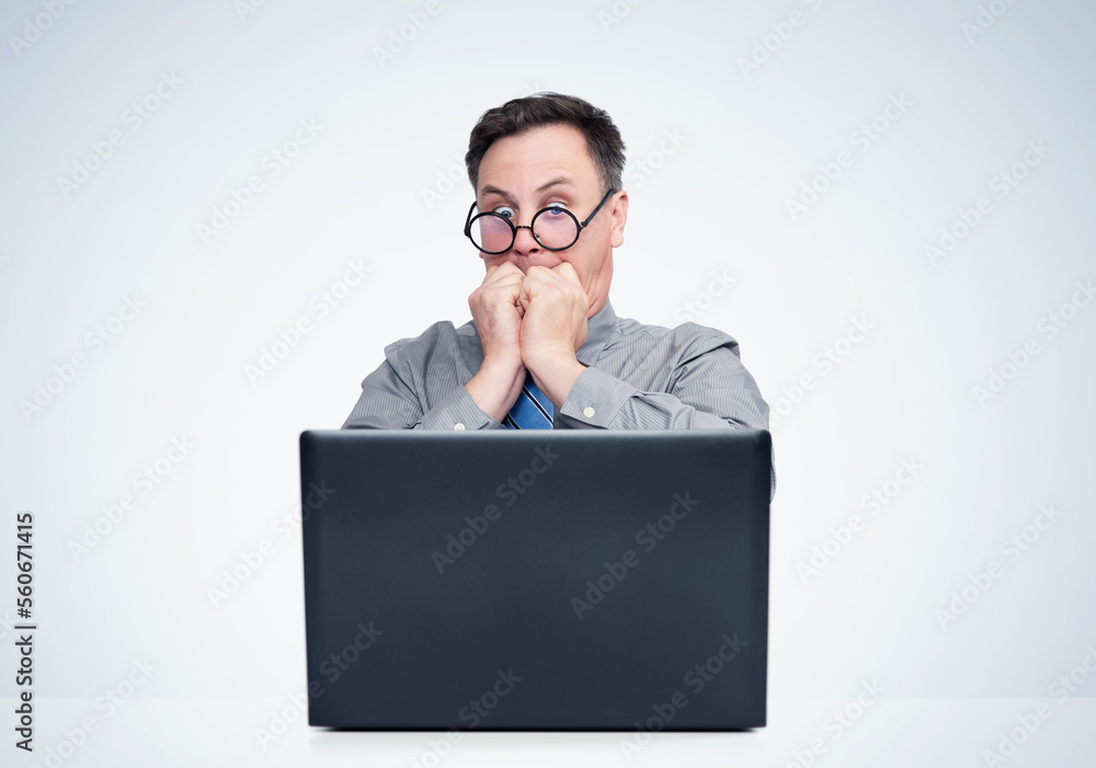 Scared man in round glasses looking at a laptop screen. Fear emotion concept Scared man in round glasses looking at a laptop screen. Fear emotion concept