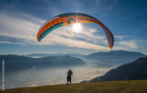 Man on a grassy slope prepare the glider for paragliding from Vetriolo Terme, Trento province - Trentino Alto Adige - Paragliding school - Italy