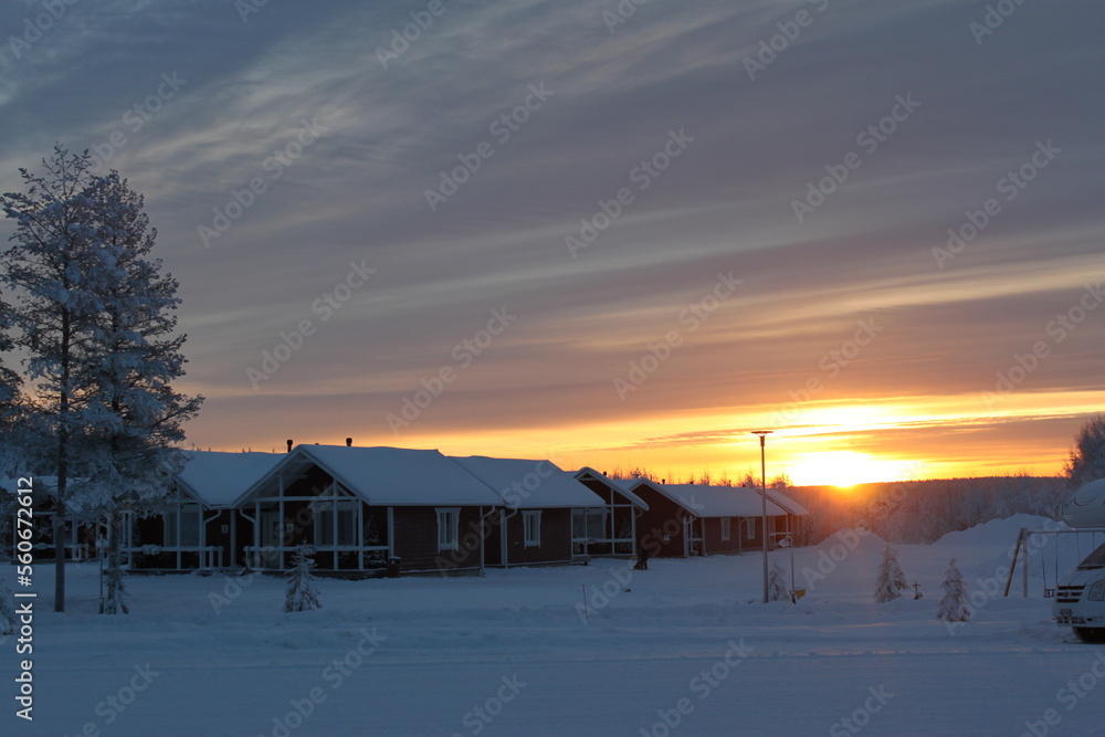 Wooden snow houses at beautiful orange sunset