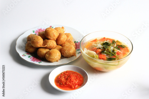 Indonesian food : Perkedel is fried patties (made of ground potatoes and minced meat), served with vegetable soup in clear bowl and chili sauce, isolated on white background