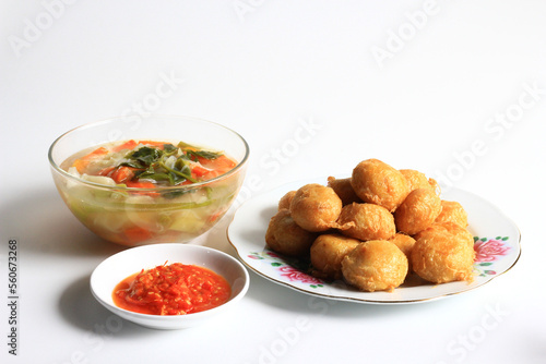 Indonesian food : Perkedel is fried patties (made of ground potatoes and minced meat), served with vegetable soup in clear bowl and chili sauce, isolated on white background