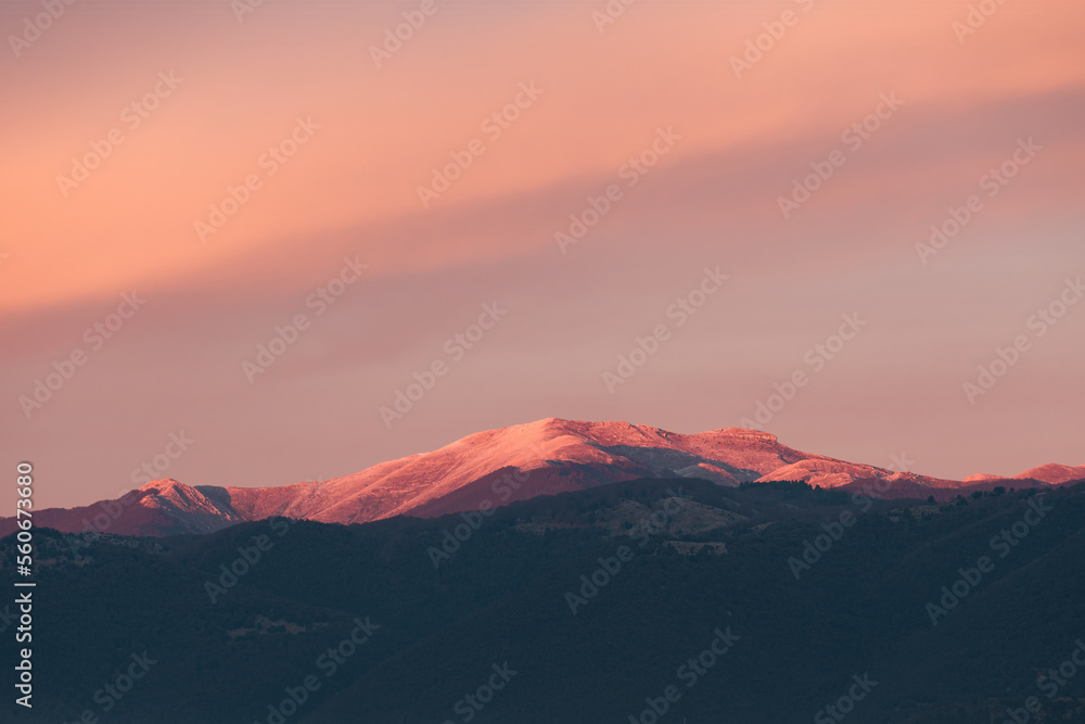 Stunning sunset with beautiful shades of orange, pink, purple and blue colors with the silhouette of a mountain range. Wallpaper, natural background with copy space.