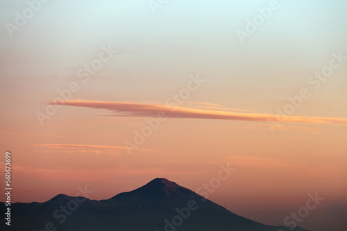 Stunning sunset with beautiful shades of orange, pink, purple and blue colors with the silhouette of a mountain range. Wallpaper, natural background with copy space.