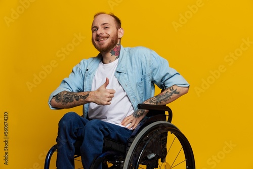 Fotografia A man in a wheelchair smile and happiness, thumb up, with tattoos on his hands s