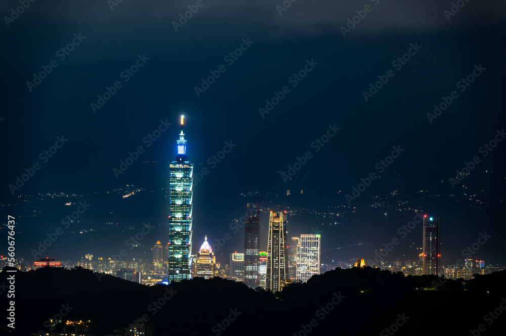 Clouds moving in the sky at night. Neon lights shine on the vibrant cityscape. Hazy and dreamy night view of the city. Taipei City, Taiwan