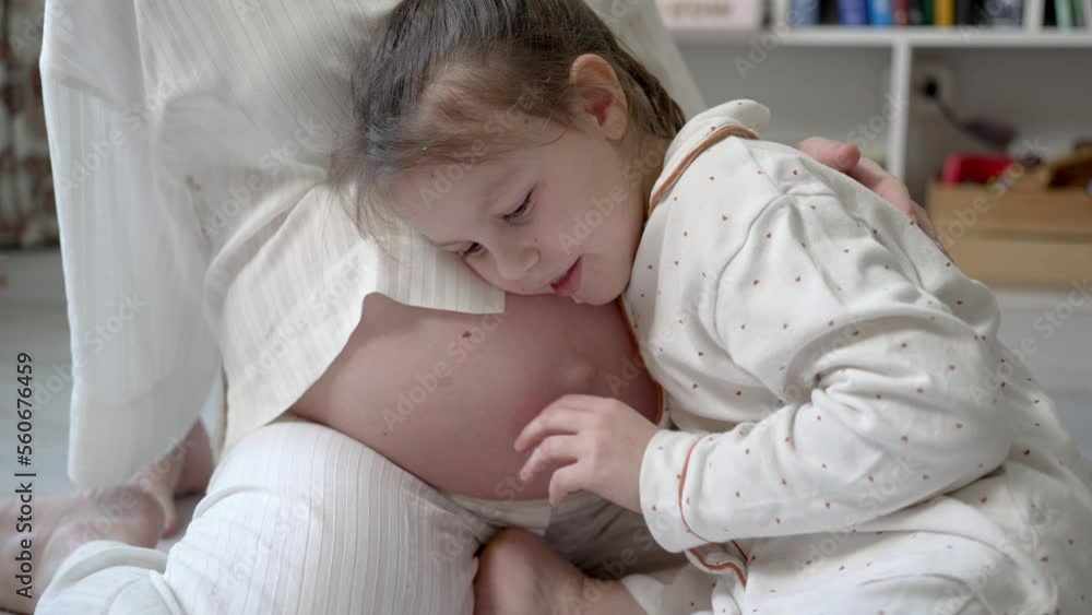 Little Girl Hugging and Put her Ear to her Pregnant Mother's Belly