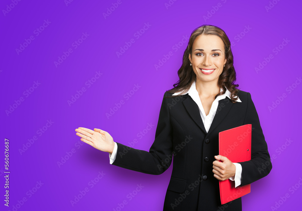 Portrait image of beautiful business woman in confident suit with red folder, showing pointing advertising, isolated on purple background. Businesswoman, executive office worker, teacher gesturing. Portrait image of beautiful business woman in confident suit with red folder, showing pointing advertising, isolated on purple background. Businesswoman, executive office worker, teacher gesturing.