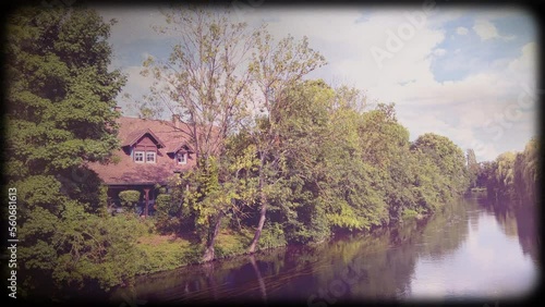 Vintage black frame with vintage film effect over calm flowing river with beautiful luxury cottage next to the shore - cinematic tale 4K UHD footage photo