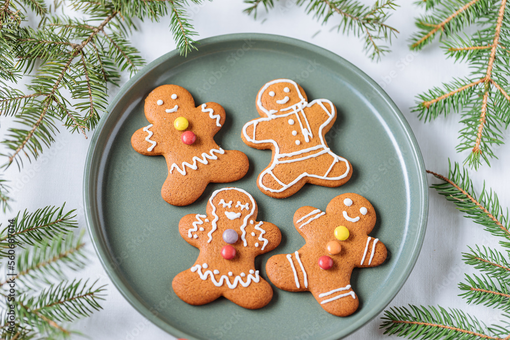 Gingerbread cookies in shape of ginger man placed on green plate with pine tree as decoration. Traditional Christmas dessert decorated. Playful and happy. Gingerbread cookies in shape of ginger man placed on green plate with pine tree as decoration. Traditional Christmas dessert decorated. Playful and happy.