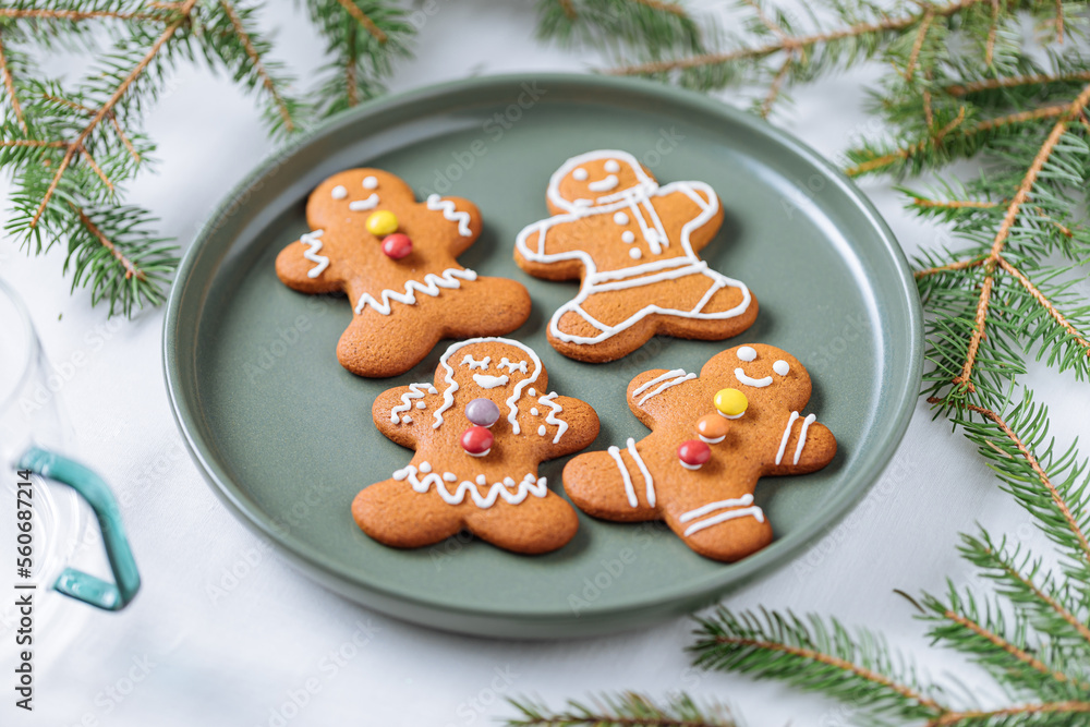 Gingerbread cookies in shape of ginger man placed on green plate with pine tree as decoration. Traditional Christmas dessert decorated. Playful and happy. Gingerbread cookies in shape of ginger man placed on green plate with pine tree as decoration. Traditional Christmas dessert decorated. Playful and happy.