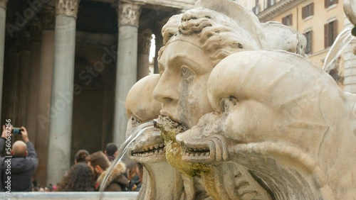 Close-up of a marble statue with a fountaint with water flowing in the famous square of the Pantheon, Rome, Italy. People and tourists on the blurred background. Selective focus. photo