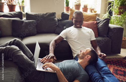 Two multiethnic gay lovers on floor with laptop photo