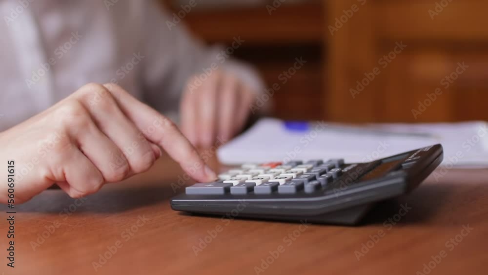 Woman hand using calculator for calculate domestic bills at home, female accountant or banker making calculations , savings, finances and economy concept Woman hand using calculator for calculate domestic bills at home, female accountant or banker making calculations , savings, finances and economy concept