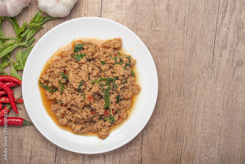 Pad kaprao, minced chicken in white plate on wooden background