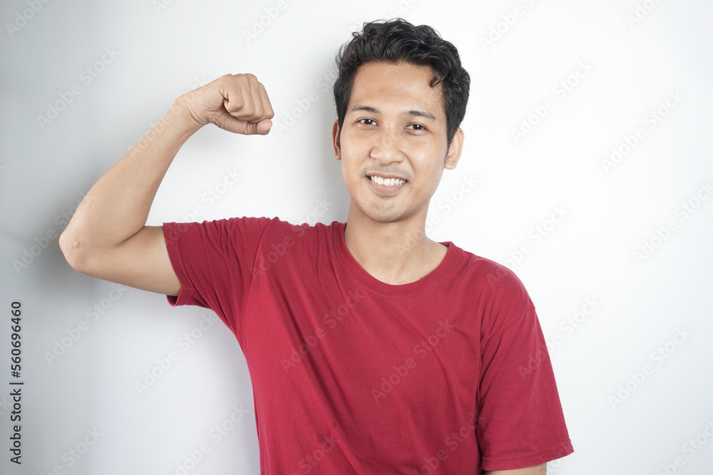 Young asian man wearing t-shirt standing over isolated white background Strong person showing arm muscle, confident and proud of power Young asian man wearing t-shirt standing over isolated white background Strong person showing arm muscle, confident and proud of power