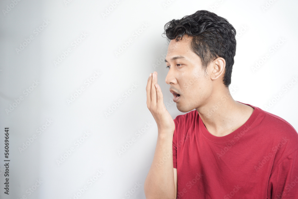 A man checks for bad breath and breathes with his hands. he has bad breath Concept of oral and dental health A man checks for bad breath and breathes with his hands. he has bad breath Concept of oral and dental health