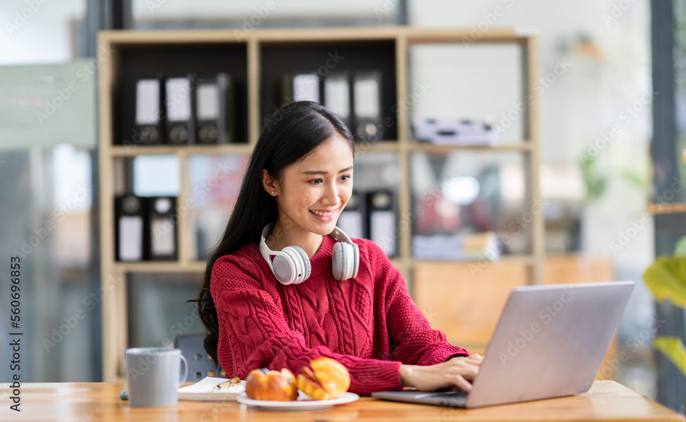 The perspective of an Asian businesswoman Sit and summarize online work orders and finances, so relax at work. By taking a break for coffee and snacks at the office.