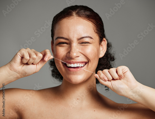 Dental floss, flossing teeth and woman with a smile for oral hygiene, health and wellness on studio background. Face of a happy female during self care, healthcare and grooming for a healthy mouth photo