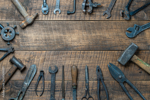 Vintage tools displayed on a background of wooden board, closeup, top view, copy space. Dirty set old working tools