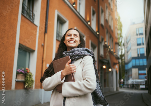 Travel, tourist and book with a sightseeing woman in the city traveling for tourism or vacation. Thinking, journal and traveling with a young female overseas or abroad for holiday in an urban town