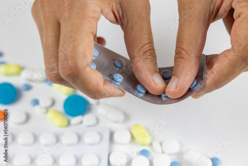 Woman removing blue pills from plastic blister.