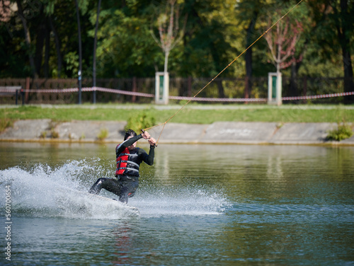 Wakeboarder surfing on lake. Young man surfer having fun wakeboarding in the cable park. Water sport, outdoor activity concept.