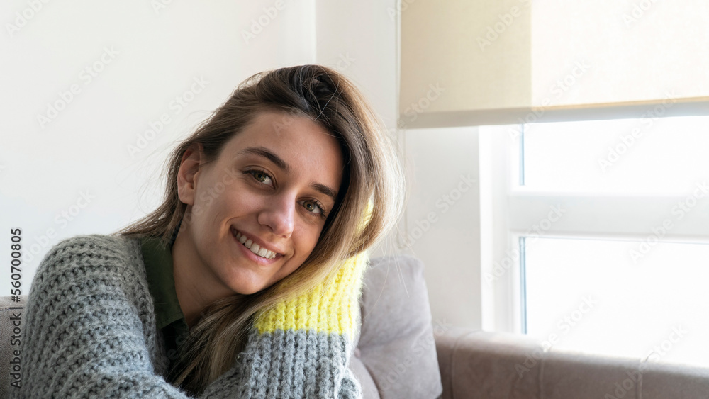 Young beautiful woman wearing comfortable and warm clothes at home in winter day. Happy woman relaxing at home. Young beautiful woman wearing comfortable and warm clothes at home in winter day. Happy woman relaxing at home.