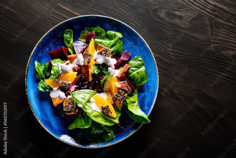 vegetarian salad with beets, spinach, orange, tofu in plate on wooden table background vegetarian salad with beets, spinach, orange, tofu in plate on wooden table background