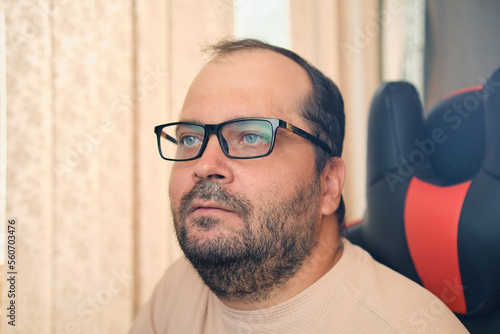 A European man in glasses works at a computer
