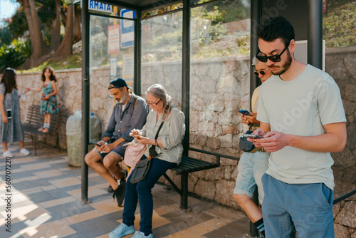 People waiting in bus stop checking their smartphones photo