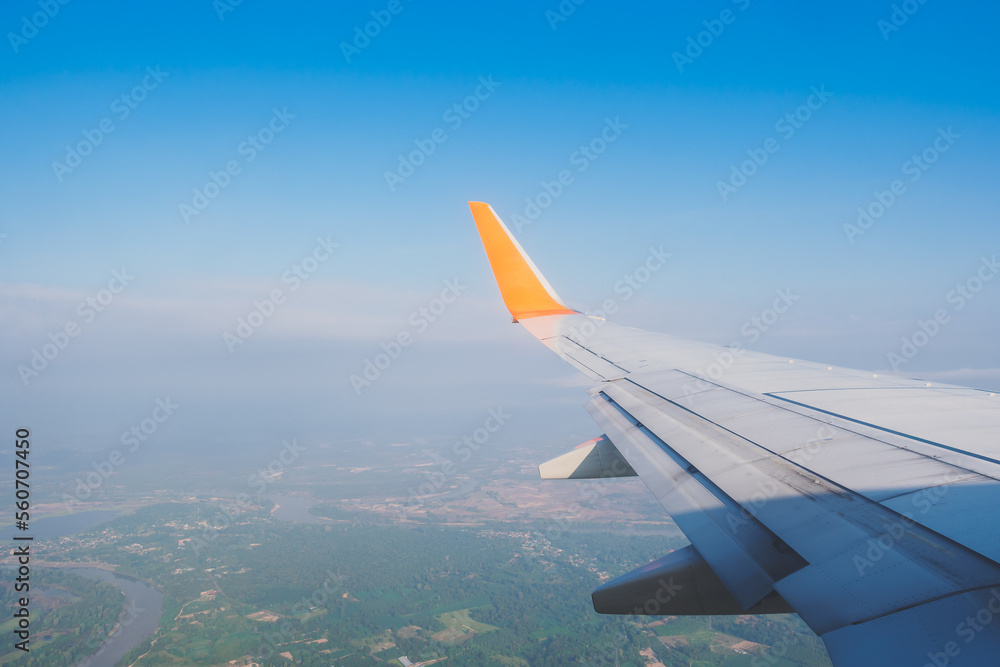 The wing tips of the airplane with clear blue sky background and lanscape view while travelling in the summer.