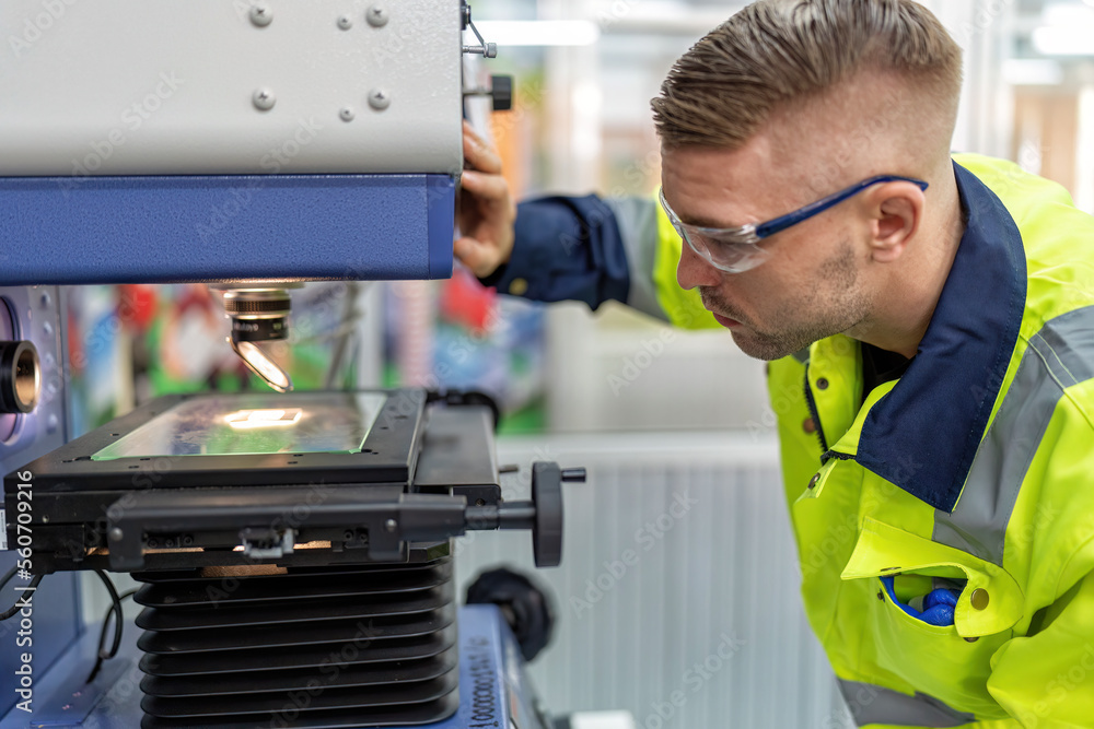 Fototapeta premium Engineer sitting in robot fabrication room use measuring microscope machine check microchip