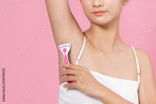 cute young girl shaves her hair on her armpits with a pink razor