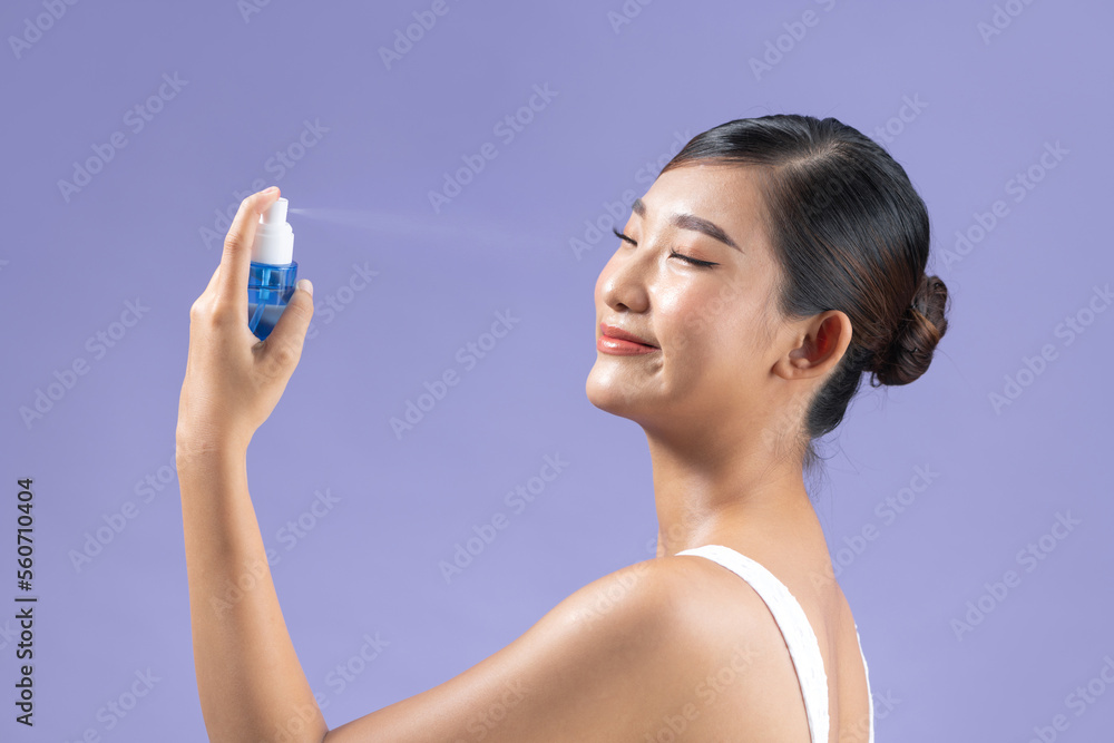 A woman spraying her face with hydrating spray A woman spraying her face with hydrating spray