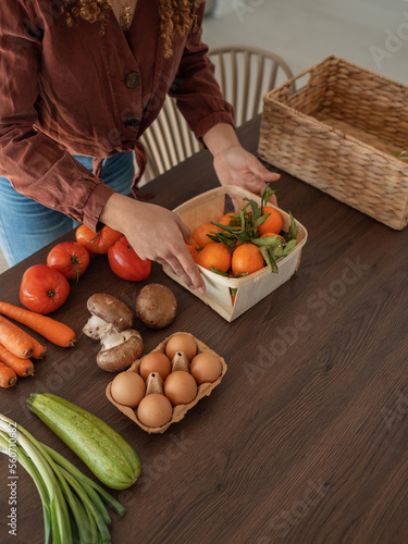 Crop female putting tangerines on table photo