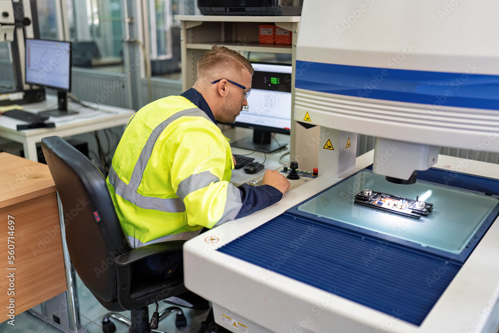 Engineer sitting in robot fabrication room use measuring microscope machine check electronic board