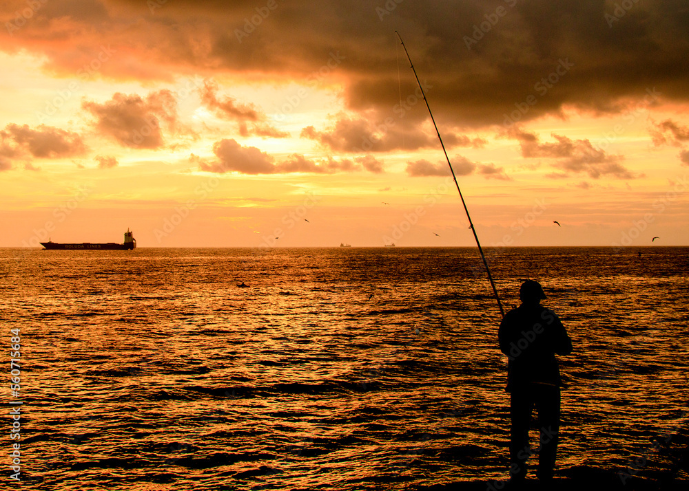 Man fishing at sunrise in the bay of Las Palmas on Gran Canaria